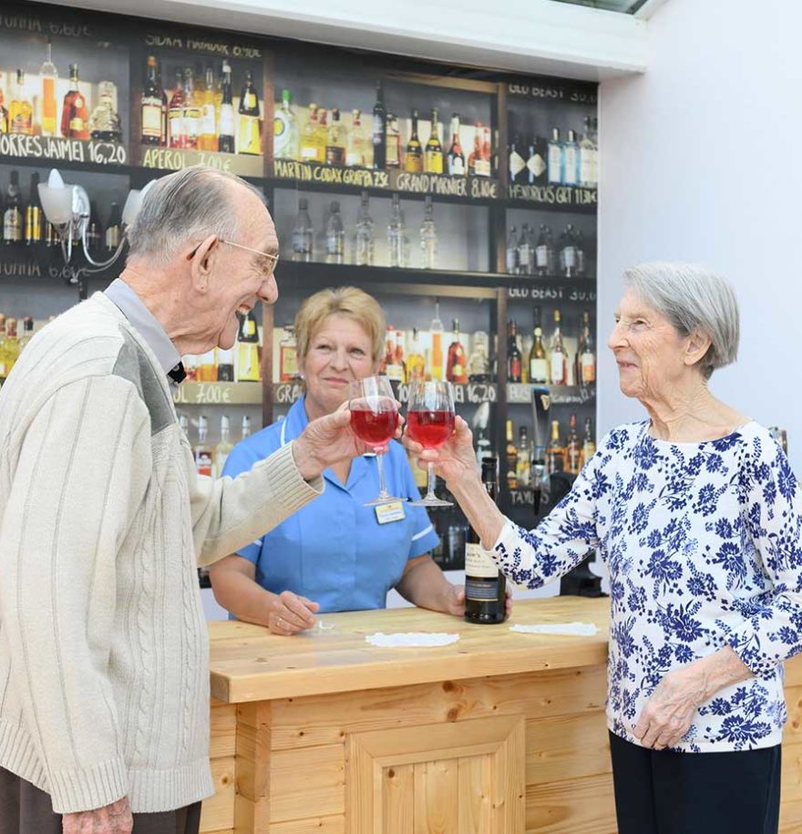 two residents smiling and doing cheer in front of bar